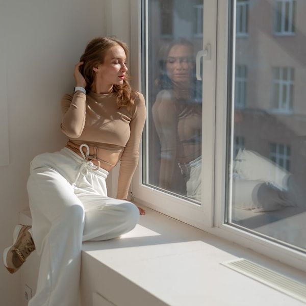A person sitting in a meditative pose with eyes closed, sunlight streaming from a window.
